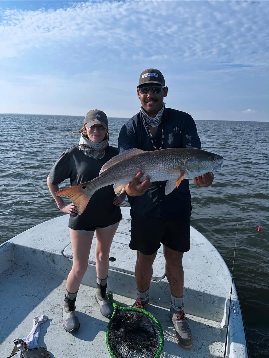 Two anglers on the boat holding a Coastal Bend redfish